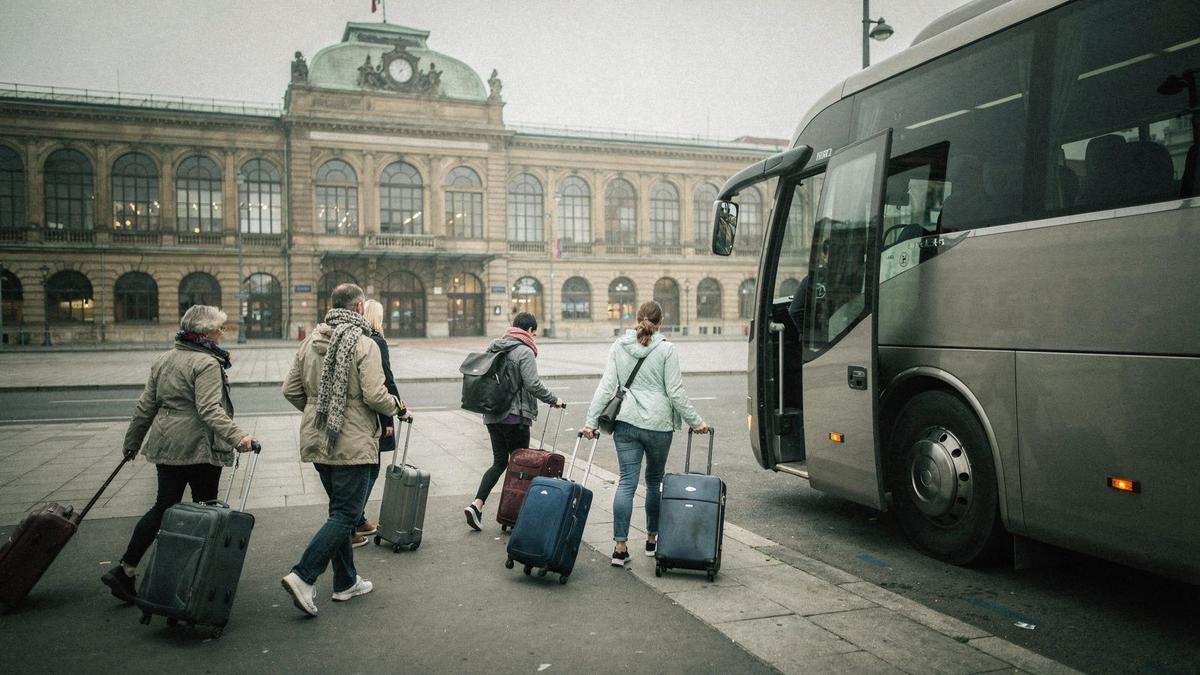 Travellers with luggage boarding a touring coach outside a Central European rail station